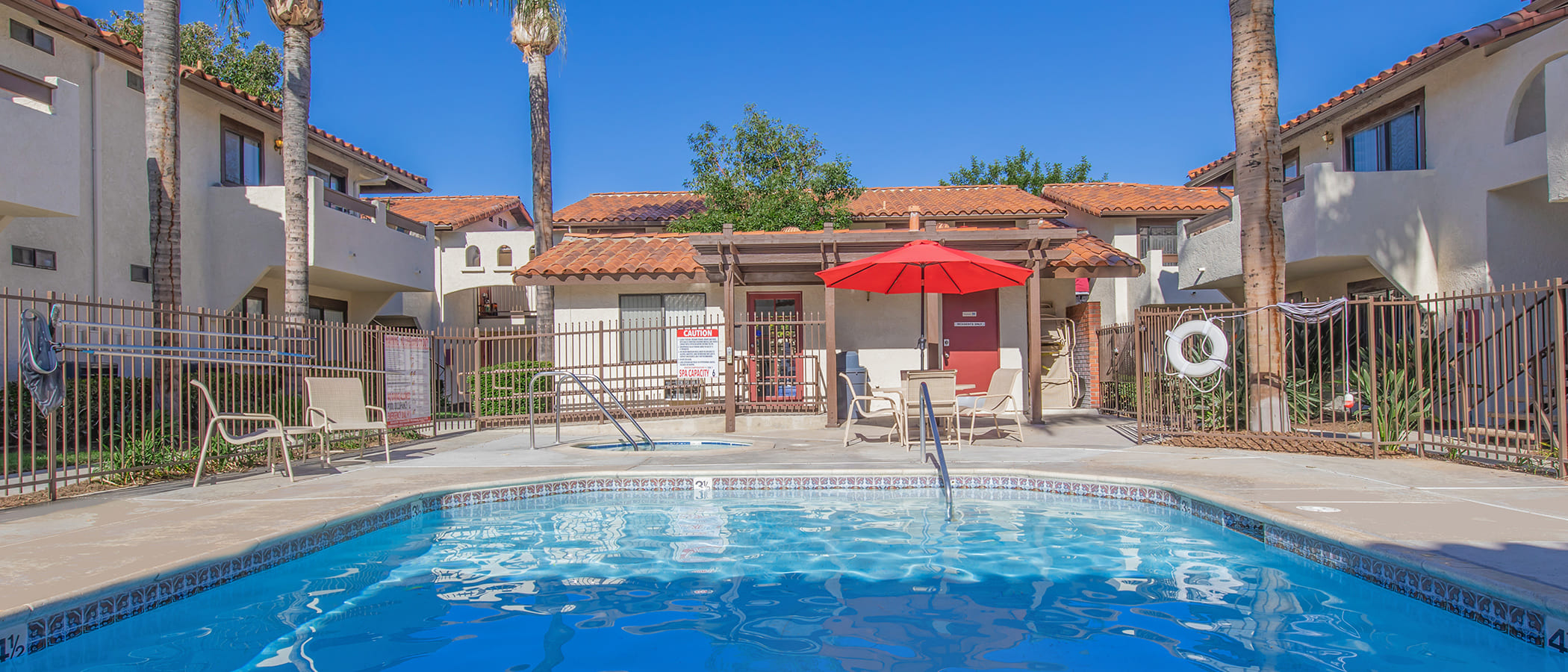 Swimming pool and hot tub with table and umbrella aet up in the area